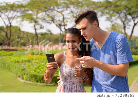 Portrait of young multi ethnic couple relaxing together at the park 73299865