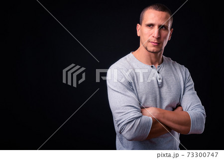 Muscular man with arms crossed against black background Muscular man with arms crossed against black background 73300747