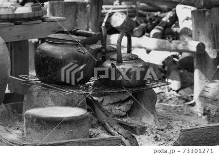 Metal kettle. Old-fashioned boiling water uses firewood to make a fire. Black and White. Metal kettle. Old-fashioned boiling water uses firewood to make a fire. Black and White. 73301271