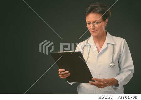 Mature beautiful woman doctor with short hair against black background 73301709