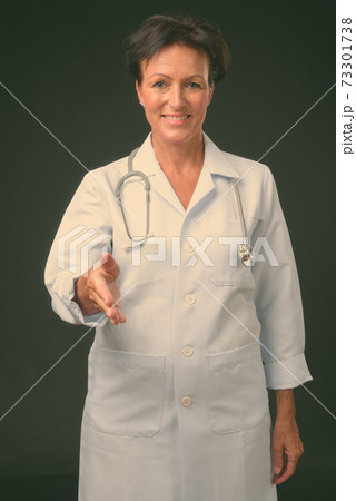 Mature beautiful woman doctor with short hair against black background 73301738