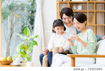 リビングで動画を見る若い家族 リビングで動画を見る若い家族 73301993