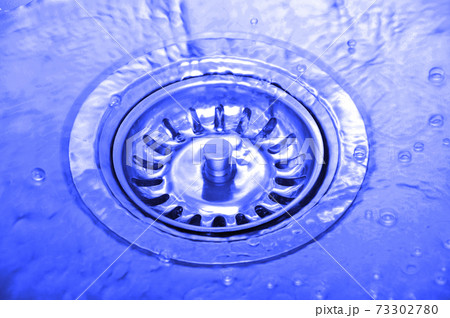 Stainless steel sink and water drain in a modern kitchen, water flow in the kitchen sink Stainless steel sink and water drain in a modern kitchen, water flow in the kitchen sink 73302780