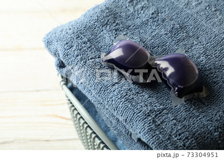 Towel with laundry capsules and detergent on white wooden background Towel with laundry capsules and detergent on white wooden background 73304951