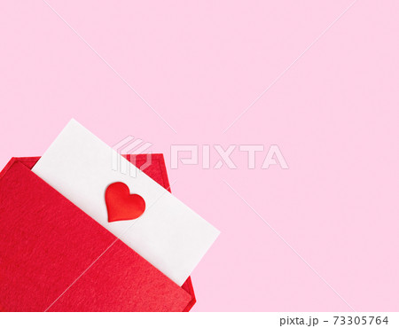 Red open envelope with a sheet of paper with a heart on a pink background with copyspace. Valentines day holidays concept and love notes, christmas and new year letters for Santa Claus 73305764