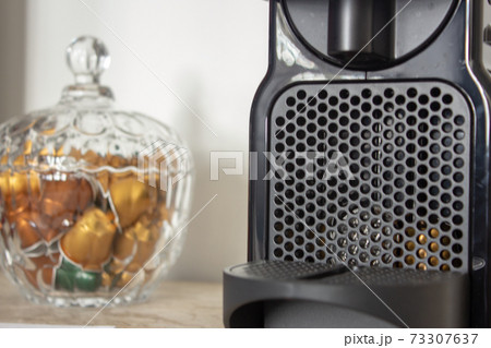 Capsule coffee machine and a glass pot full of capsules 73307637