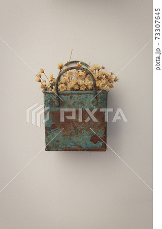 Bunch of tinny artificial flowers, hay colored, inside a blue metal box, very old and rusted, hanging on the wall Bunch of tinny artificial flowers, hay colored, inside a blue metal box, very old and rusted, hanging on the wall 73307645
