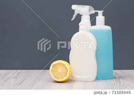 Bottles of dishwashing liquid and lemon on gray background. 73309340