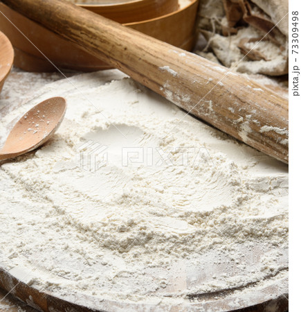 white wheat flour and wooden rolling pin on board, baking ingredients 73309498