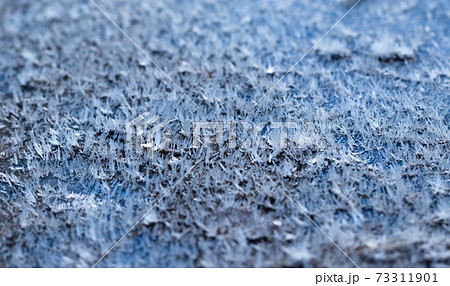 White hoarfrost crystals on flat surface closeup, blue background 73311901