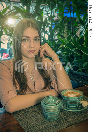 Nice lady sitting in cafeteria with some milk coffee served in front on her Nice lady sitting in cafeteria with some milk coffee served in front on her 73312591