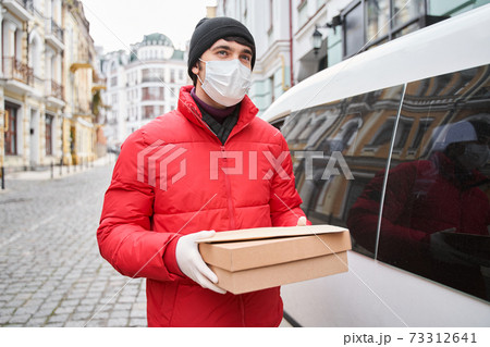 Delivery man going with cardboard box in his hands 73312641