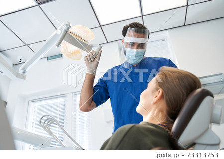 Serious male dentist working in dental clinic with female patient 73313753