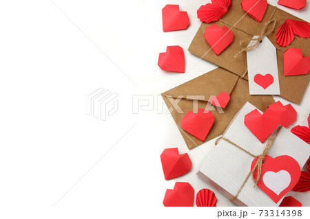 White gift box with red label in a heart form, gift wrapped in brown craft paper, tied with twine with a bow, envelope from craft paper with red heart, 3D paper hearts on white background isolated White gift box with red label in a heart form, gift wrapped in brown craft paper, tied with twine with a bow, envelope from craft paper with red heart, 3D paper hearts on white background isolated 73314398