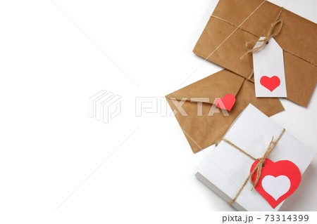 White gift box with red label in a heart form, gift wrapped in brown craft paper, tied with twine with a bow, envelope from craft paper with red heart on white background isolated White gift box with red label in a heart form, gift wrapped in brown craft paper, tied with twine with a bow, envelope from craft paper with red heart on white background isolated 73314399