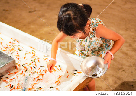 夜店の金魚すくいをする女の子の写真素材