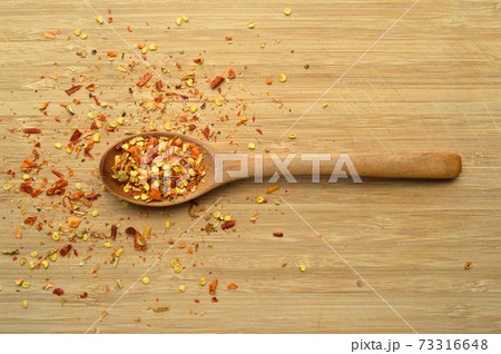 Dried red pepper in wooden spoon on bamboo cutting board 73316648
