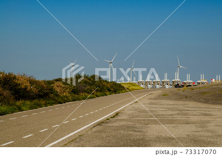 Netherlands, August 2019. In Zeeland, wind farms are the setting for the immense dam that governs the flow of sea waters, securing the territory. Netherlands, August 2019. In Zeeland, wind farms are the setting for the immense dam that governs the flow of sea waters, securing the territory. 73317070