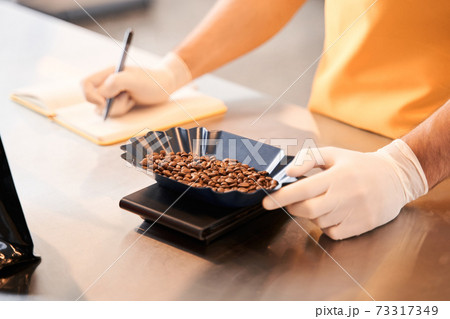 Man weighing coffee beans before the filling bags 73317349