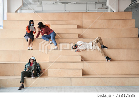Attractive groupmates spending time together at the stairs Attractive groupmates spending time together at the stairs 73317838