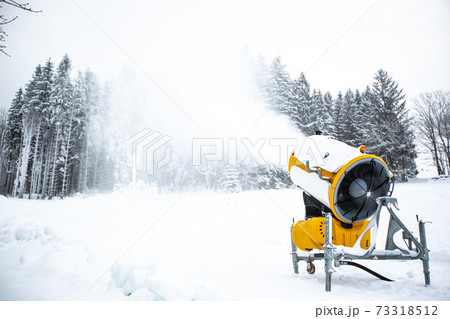 Snow cannon, machine or gun snowing the slopes or mountain for skiers ans snowboarders, artificial snow 73318512