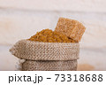 Brown cane sugar in a bag with a cube of shed on top 73318688