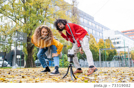 Young couple with smartphone making video for social media outdoors in park. Young couple with smartphone making video for social media outdoors in park. 73319082
