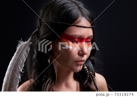 young indian shamanic female with Indian feather wearing and colorful makeup 73319274