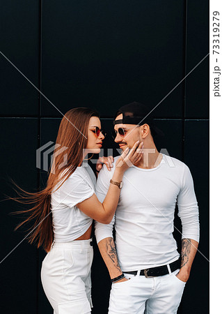 A beautiful couple in love in white stylish clothes are walking in the city 73319279