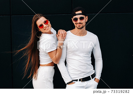 A beautiful couple in love in white stylish clothes are walking in the city 73319282