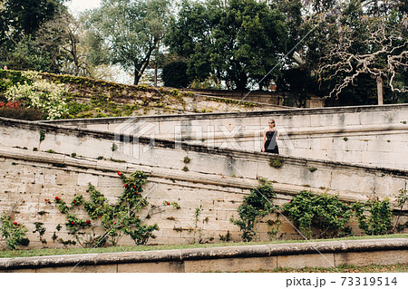 A stylish bride in a black wedding dress poses in the ancient French city of Avignon. Model in a beautiful black dress. Photo shoot in Provence. 73319514