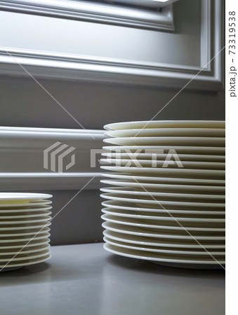 Stack of ceramic plates or pile of porcelain dishes in a kitchen of a restaurant or cafe. Catering buffet in restaurant room. Concept preparing for celebration Stack of ceramic plates or pile of porcelain dishes in a kitchen of a restaurant or cafe. Catering buffet in restaurant room. Concept preparing for celebration 73319538