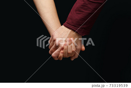 Male hand holds female hand on dark background 73319539