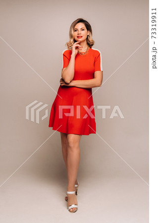 A girl in a red dress poses on a white background 73319911
