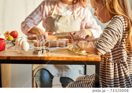 caucasian family child with mother rolling out the dough 73320008