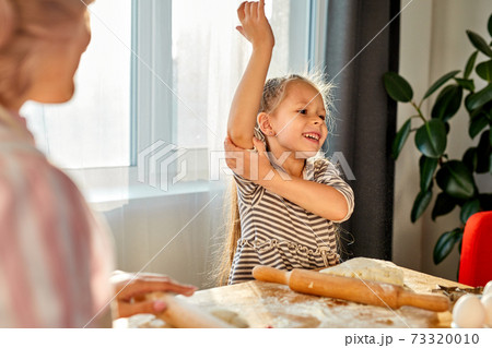 child girl wraps up the sleeves before cooking 73320010