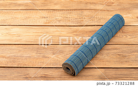 Rolled up bamboo blue food mat on wooden background. 73321288