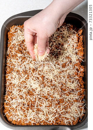 Sprinkle the grated cheese on a layer of minced meat with tomato paste. Sprinkle the grated cheese on a layer of minced meat with tomato paste. 73321305