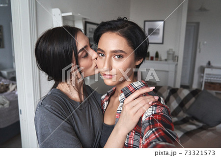 Young lesbian couple kissing taking selfie at..