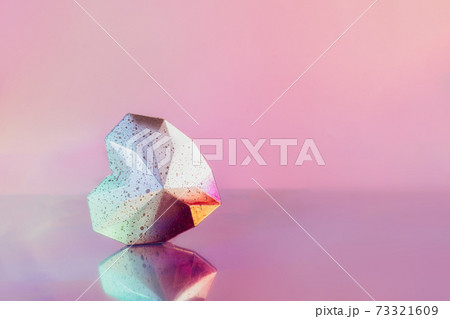 Sparkling geometric heart with a reflection on a neon pink background. Dotted gradient white and pink polygonal heart lying on glancing surface. Modern Creative Valentine's day card. Minimalist style. 73321609