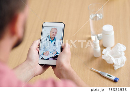 Mature male doctor on smartphone screen giving medical recommendations 73321938