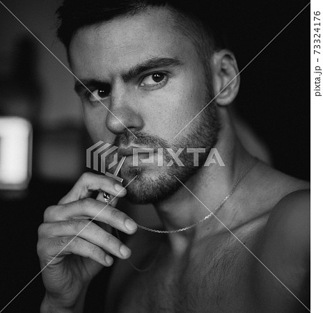 The man covers his face with his hand, looking at the camera The man covers his face with his hand, looking at the camera 73324176