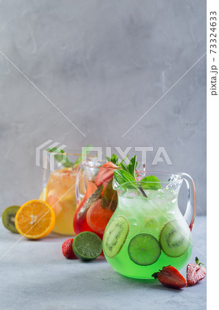 Different color lemonade in glass decanters with fruits and garnished with fresh mint and sliced Different color lemonade in glass decanters with fruits and garnished with fresh mint and sliced 73324633