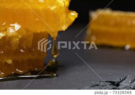 gloden broken honeycomb slices with dripping fresh honey on blur background gloden broken honeycomb slices with dripping fresh honey on blur background 73326569