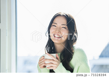 窓際で飲み物を飲む若い女性 73328394