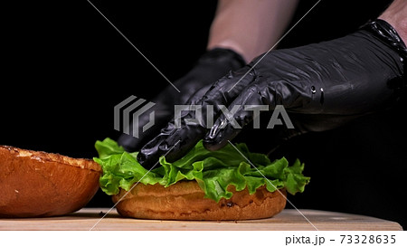 Craft burger is cooking on black background. Consist: sauce, lettuce, tomato, red onion, pickle, cheese, bacon, air bun and marbled meat beef. 73328635