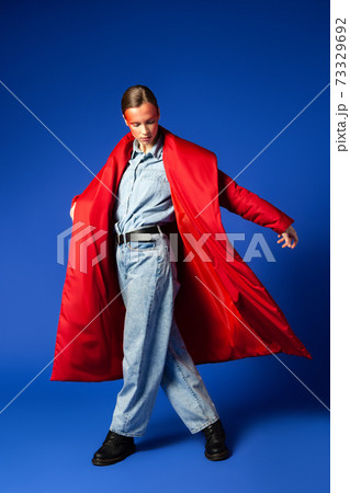 Woman in stylish coat dancing against blue background Woman in stylish coat dancing against blue background 73329692