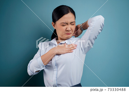 Asian woman testing smelling her armpit. 73330488