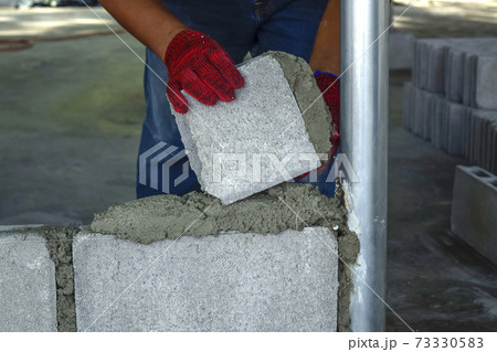 Plaster worker wearing red gloves is laying bricks. Plaster worker wearing red gloves is laying bricks. 73330583