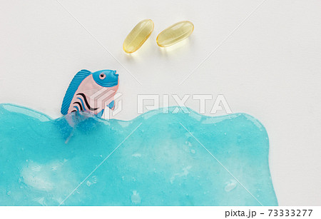 Fish collagen capsules and fish on blue background. Fish collagen capsules and fish on blue background. 73333277